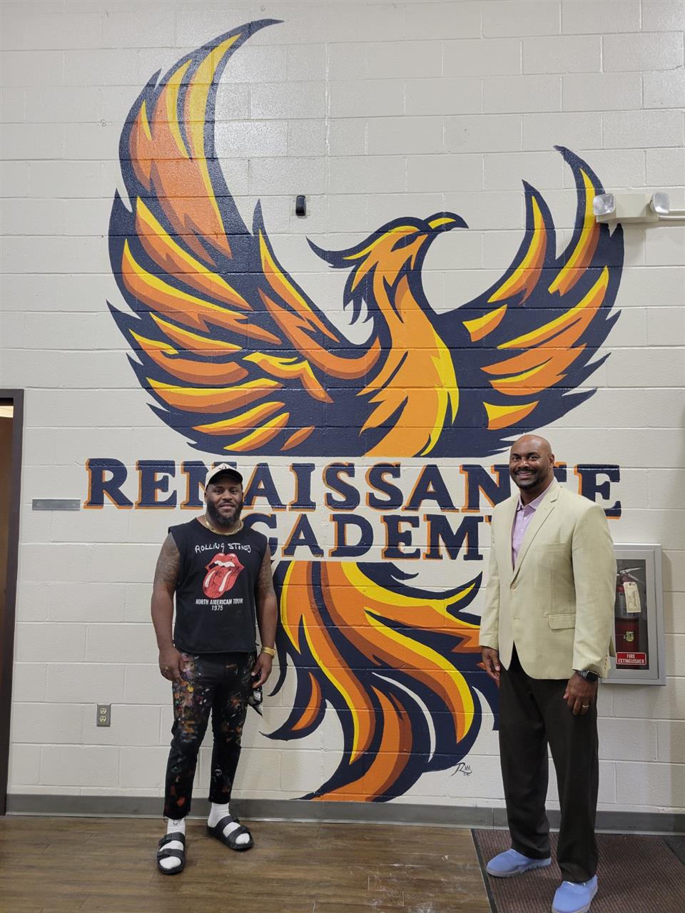 School director, Mr. McGowens, stands next to artist Shaquille Ellis in front of phoenix mural